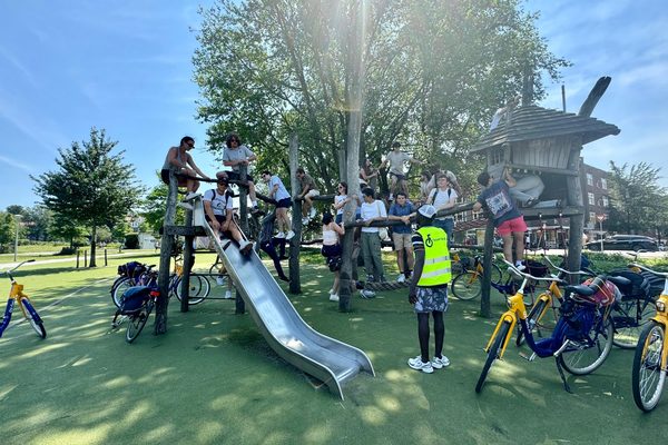 Participants gathered on a wooden playground structure with their rental bicycles parked around it.