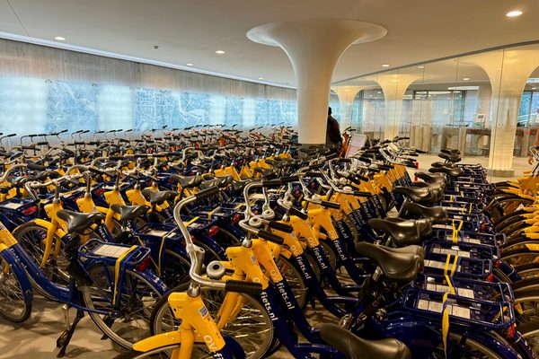 Rows of blue and yellow OV-fiets rental bicycles parked inside an underground station bicycle facility.