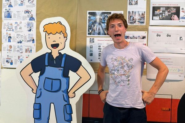 A participant beside a technician cutout at a transit operator depot display of posters and diagrams.