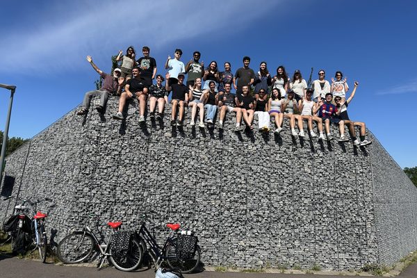 Program participants sitting on top of a stone-filled gabion noise barrier with their bicycles parked below.