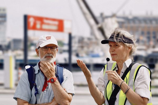 A guide in a high-visibility vest explaining a site to a participant during an outdoor field visit.