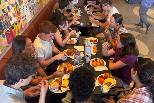 Participants sharing breakfast around long tables in a common room before a field visit.